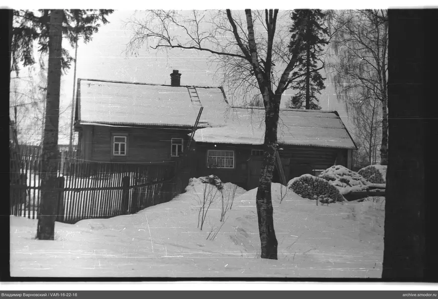 Holzhaus mit Schnee und Holzstapeln
