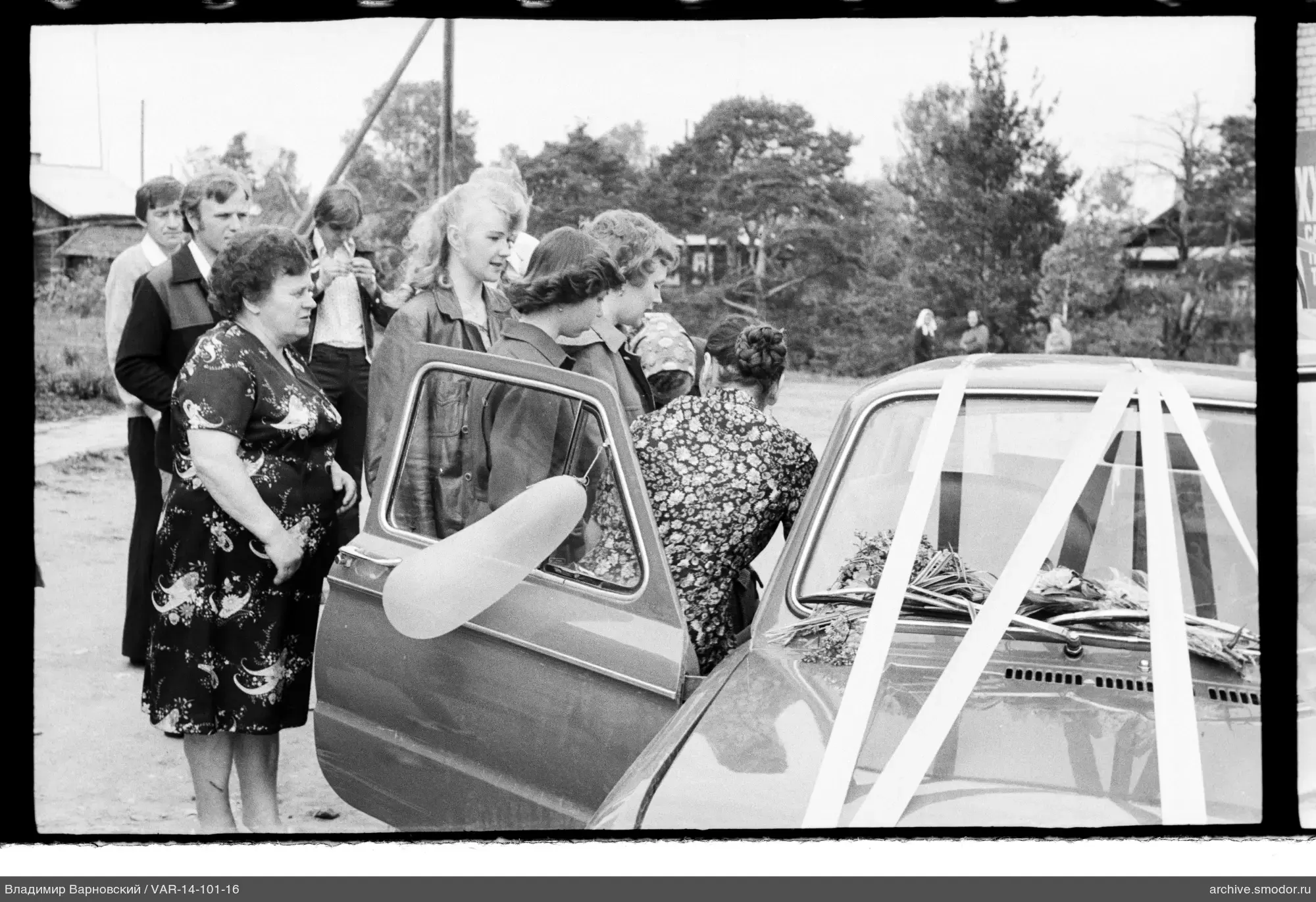 Gruppe bei Auto mit Blumen und Bändern