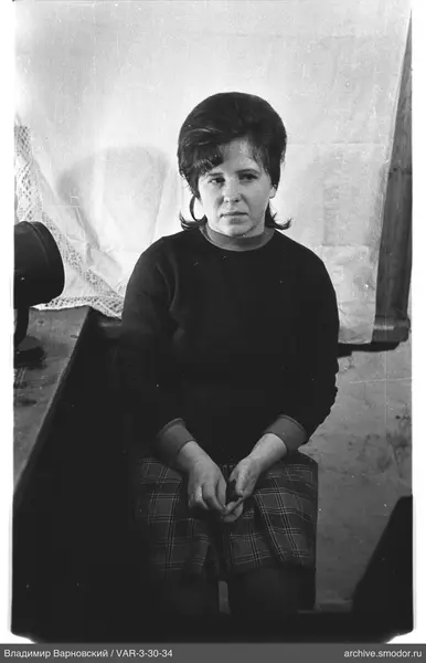 Portrait of a seated woman in dark sweater and plaid skirt