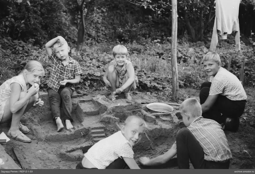 Gruppe von Kindern um eine Sandkonstruktion
