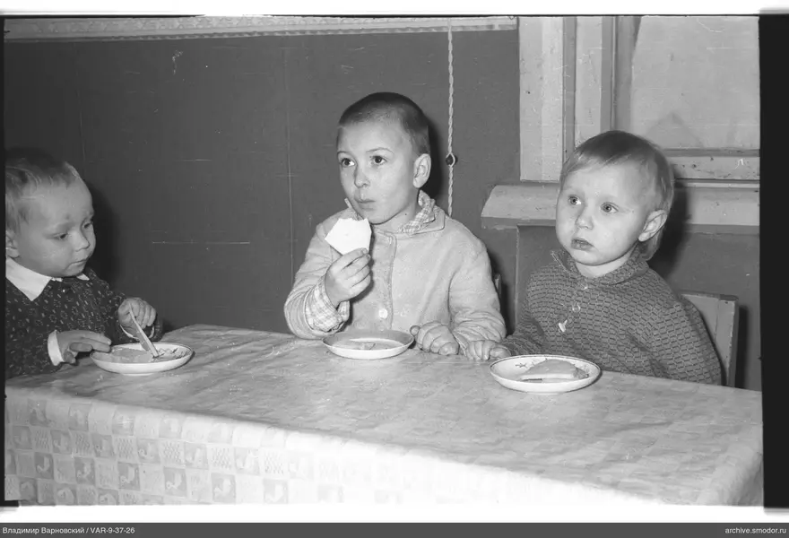 Drei Kinder am Tisch mit Brot und Löffel