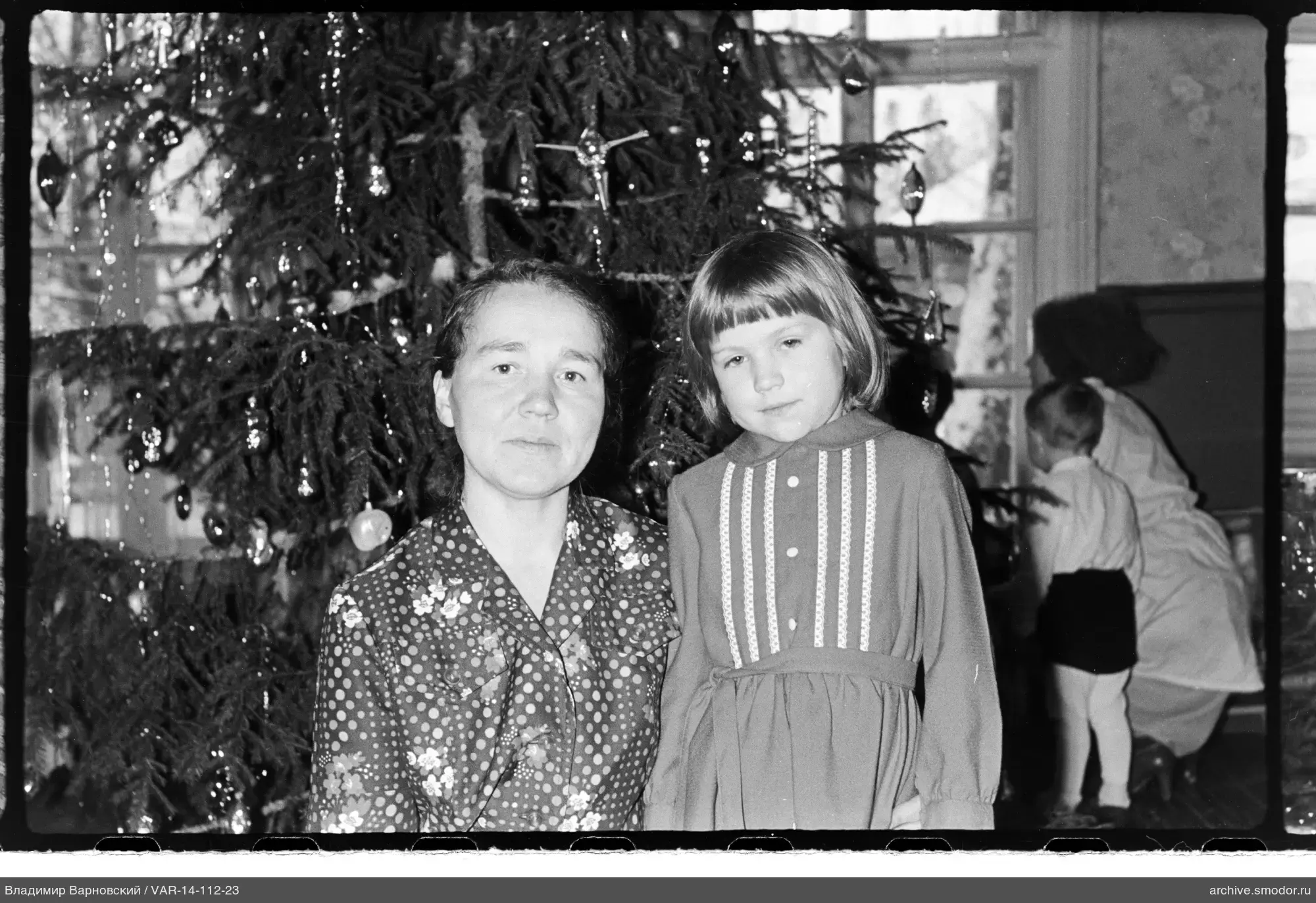Frau und Mädchen neben geschmücktem Weihnachtsbaum
