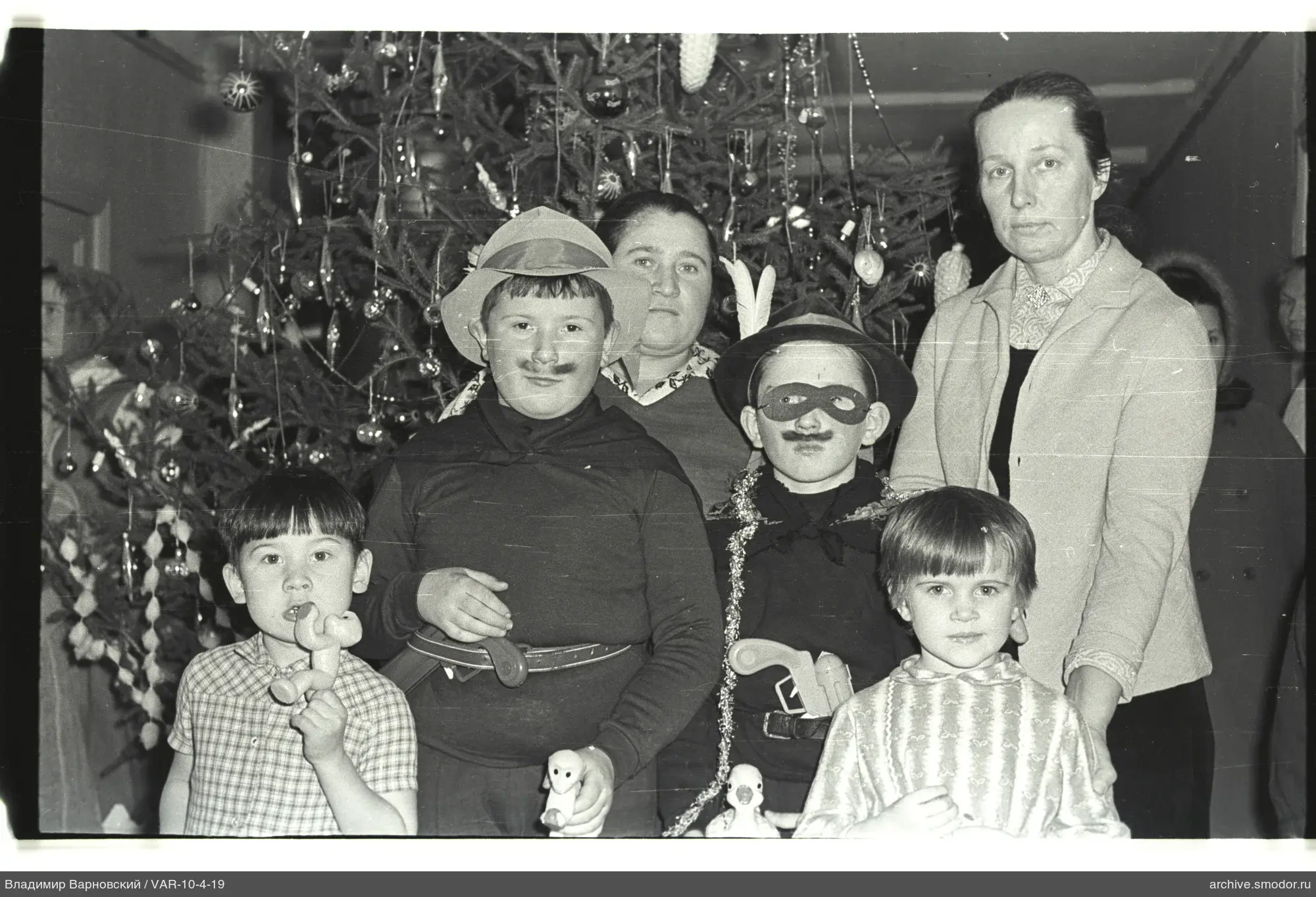 Kinder und Frauen bei geschmücktem Weihnachtsbaum