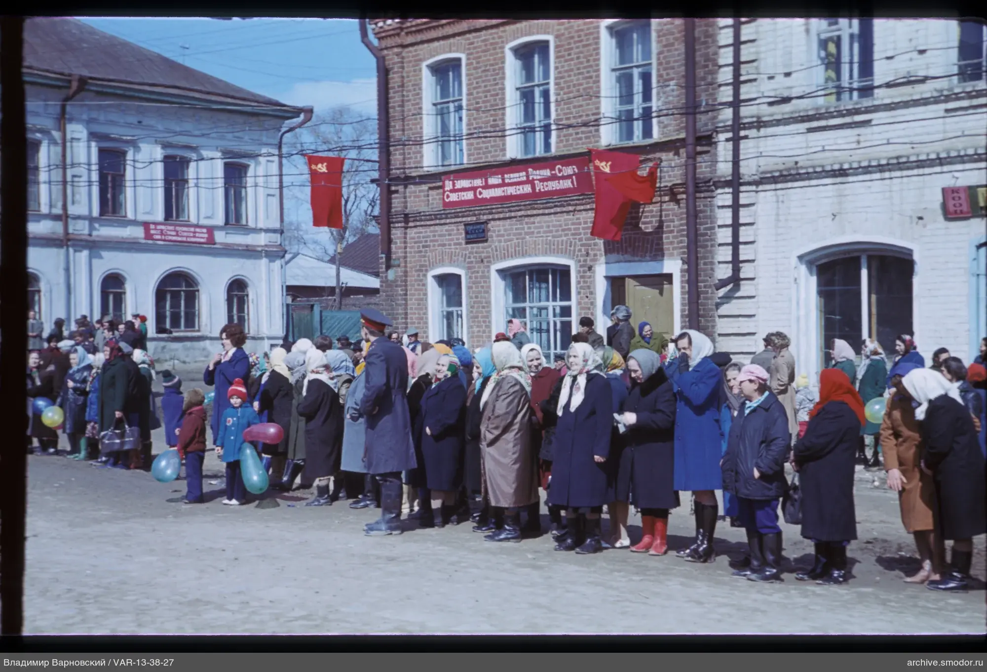 Gruppe von Menschen vor Ziegelgebäude mit Fahnen