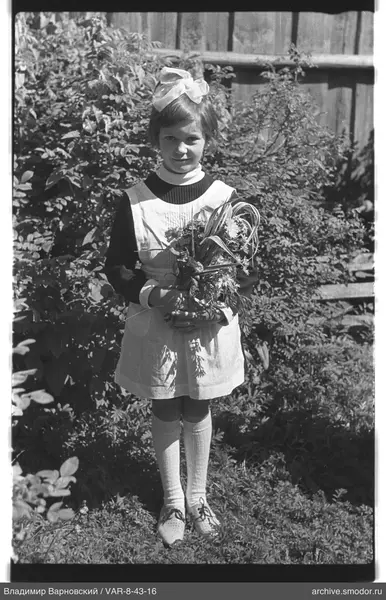 Mädchen mit Blumenstrauß vor Zaun