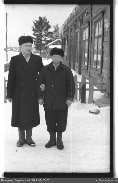 Два мужчины на заснеженной улице у деревянного дома