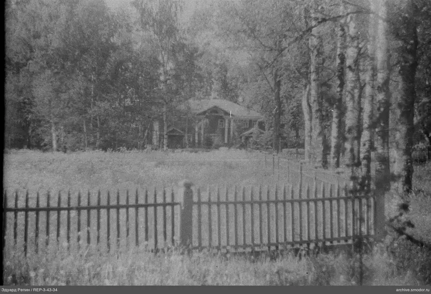 Holzzaun und Haus mit Bäumen