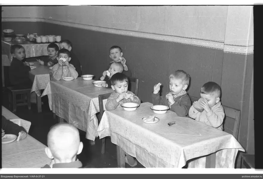 Children sitting at tables with bread and cups