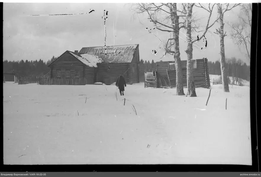 Person geht zu Holzhaus im Schnee