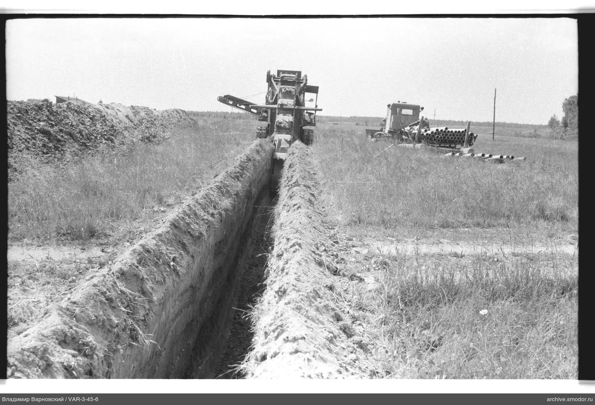 Bagger und LKW mit Rohren