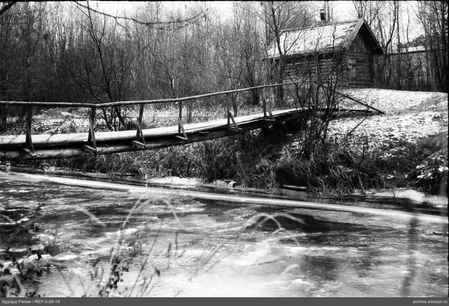 Holzbrücke und Haus am zugefrorenen Wasser
