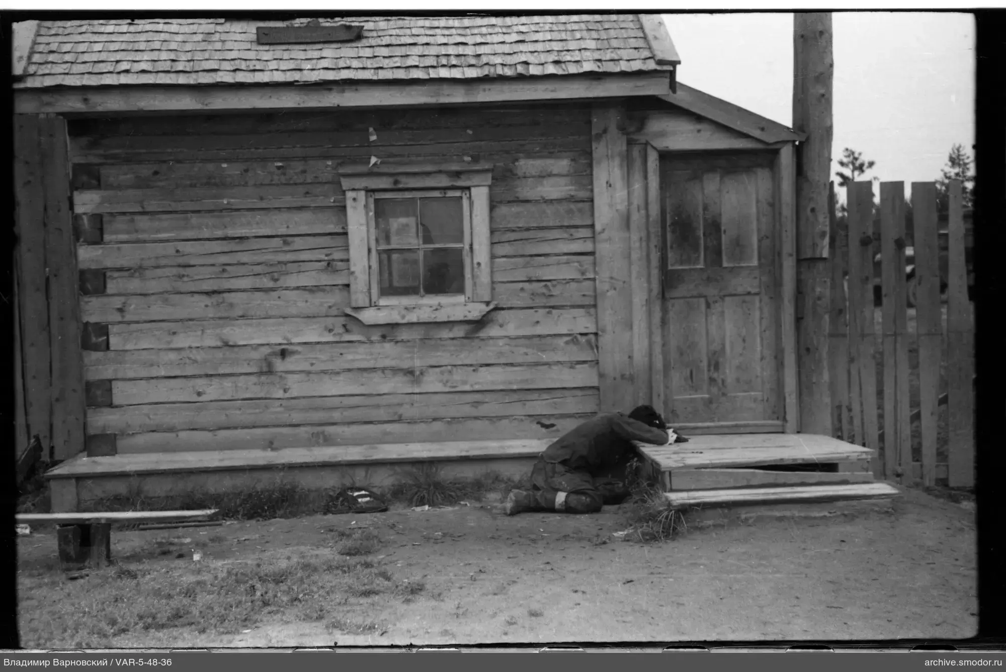 Man kneeling by wooden house