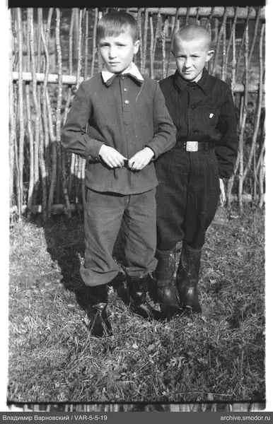 Zwei Jungen auf dem Gras vor einem Zaun