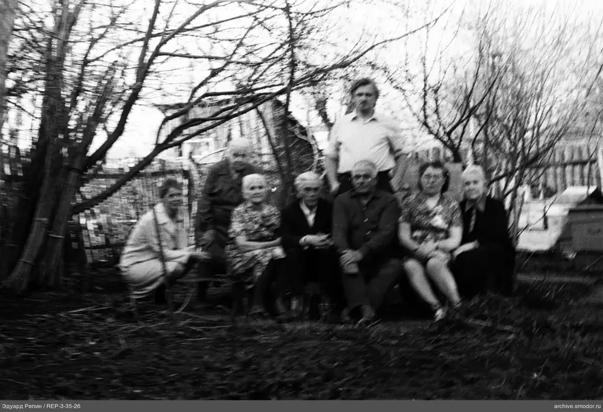 Gruppe von Menschen vor Zaun und Haus