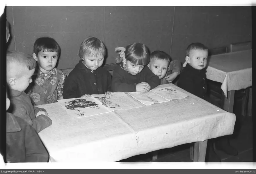 Children sitting at a table with drawings