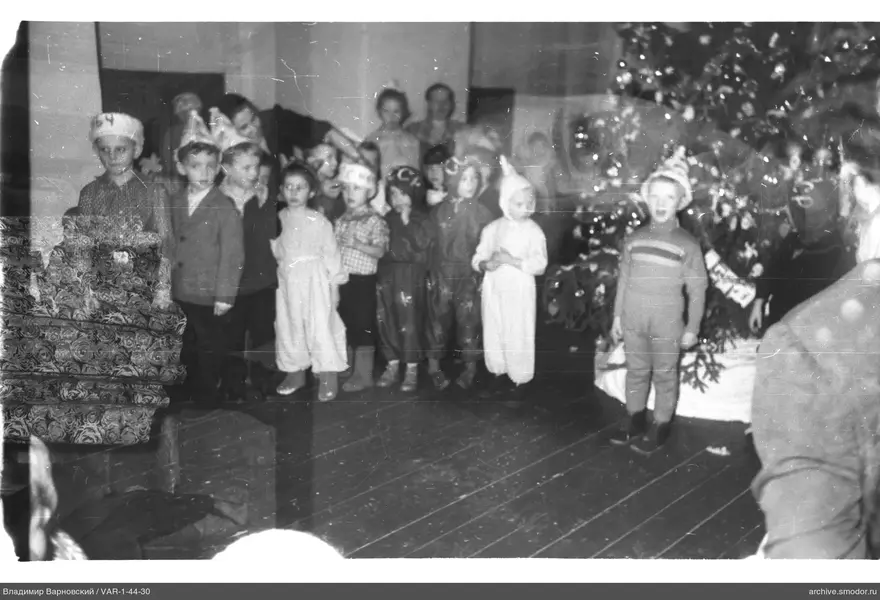 Kinder in Kostümen bei geschmücktem Weihnachtsbaum