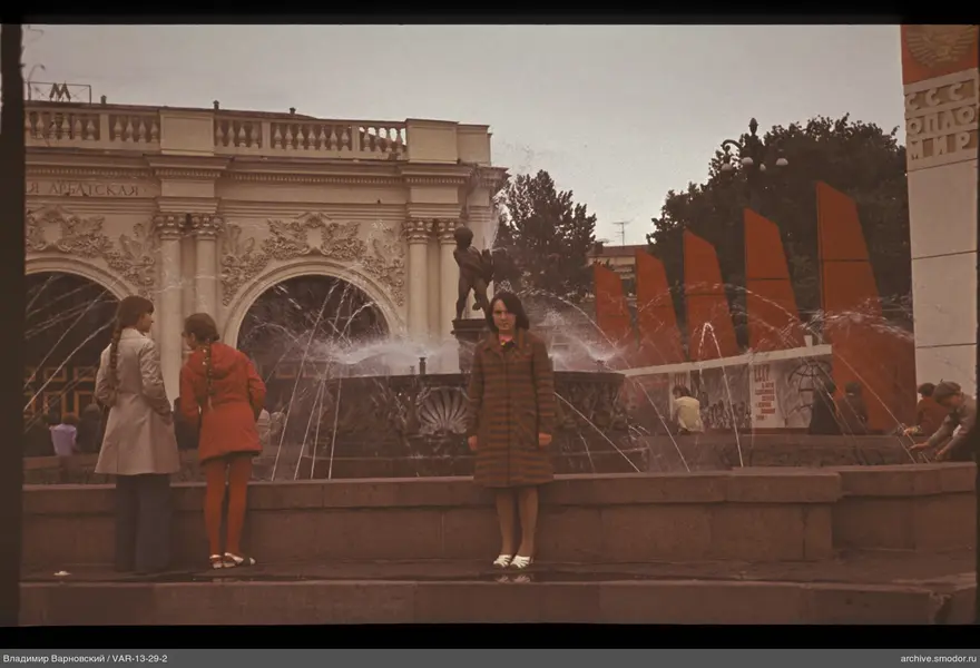 Frau am Brunnen und Mädchen vor Gebäude