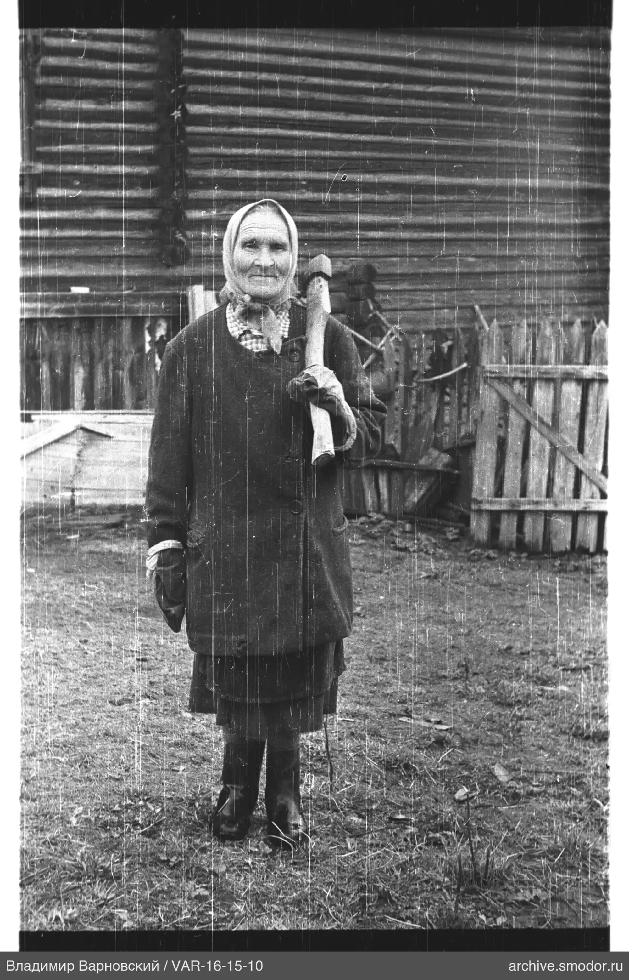 Woman with axe in front of wooden house