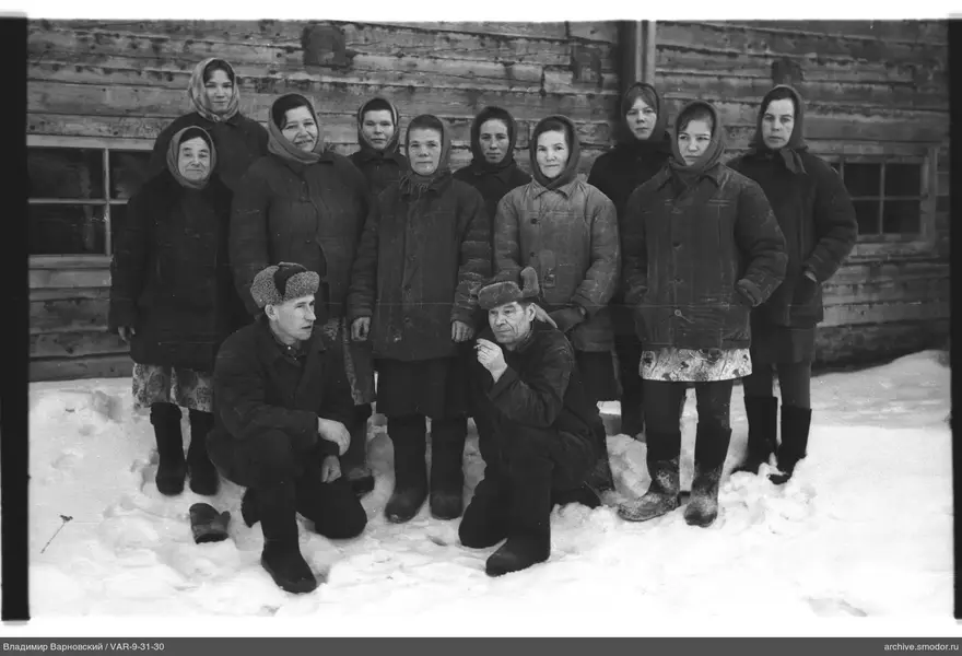 Gruppenporträt auf Schnee vor Holzgebäude
