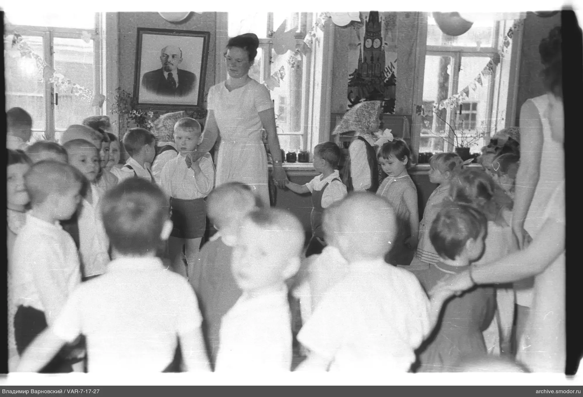 Kinder und Frauen im Raum mit Lenin-Porträt