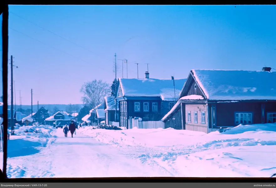 Snow-covered street with wooden houses