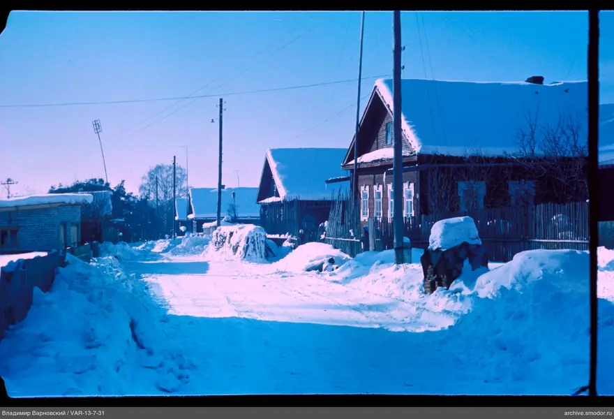 Snow-covered street with wooden houses