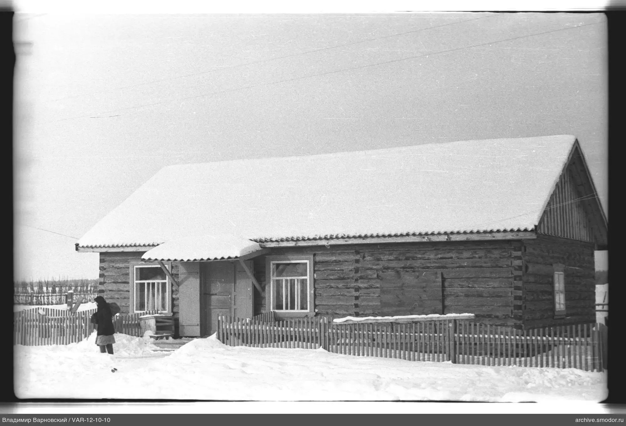 Holzhaus mit Frau im Vordergrund