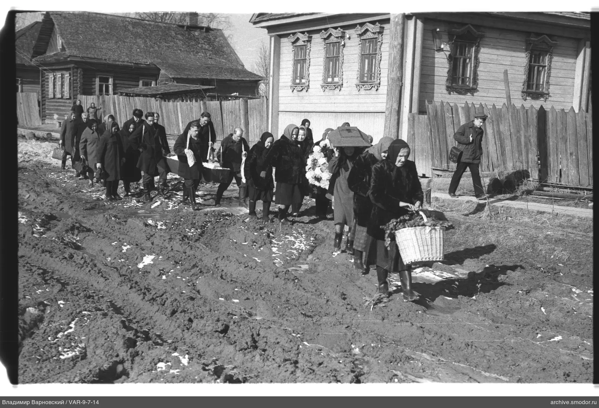 Gruppe von Menschen auf der Straße mit Sarg und Blumenkorb
