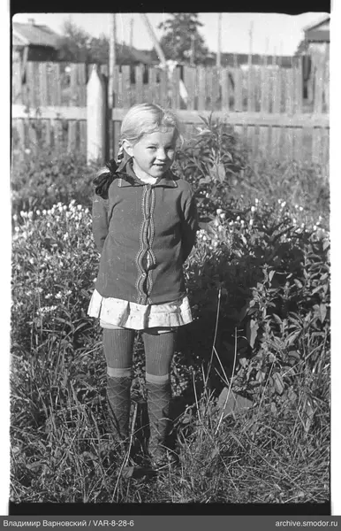 Mädchen im Gras mit Kleid und Pullover