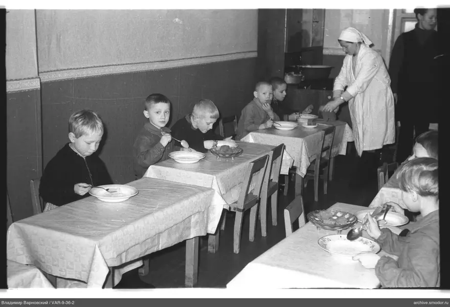 Children at tables and woman setting the table