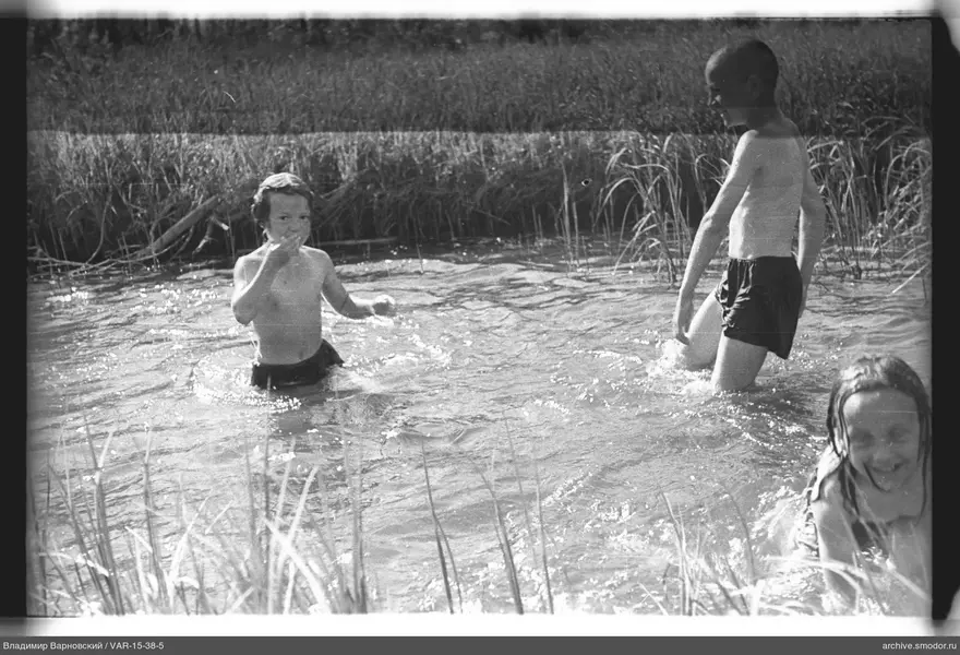 Kinder im Wasser am grasbewachsenen Ufer