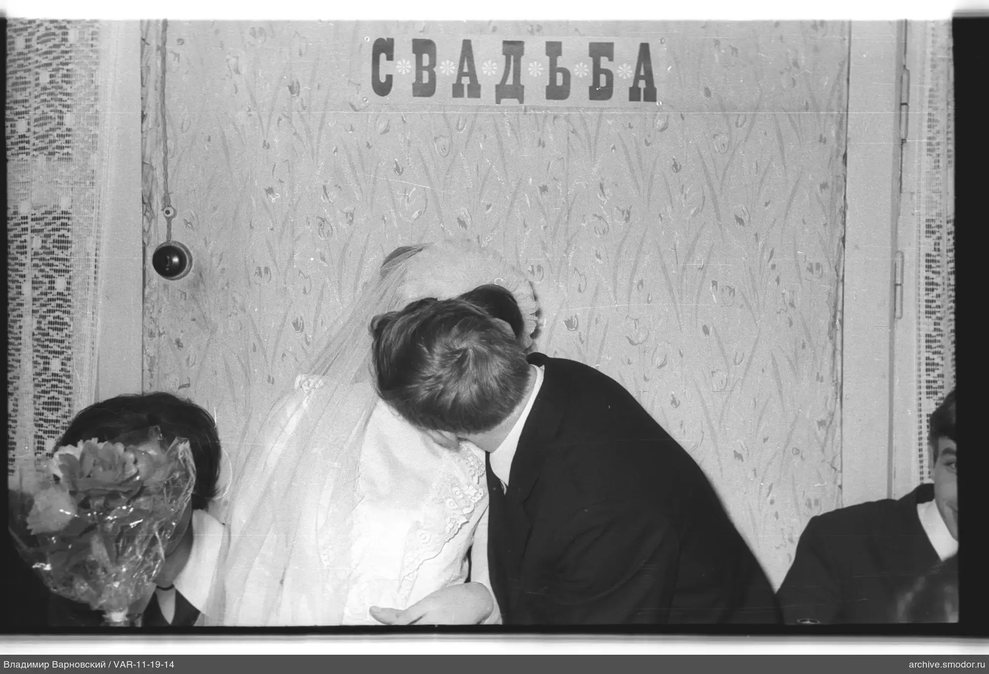 Молодожены целуются на фоне надписи «Свадьба»