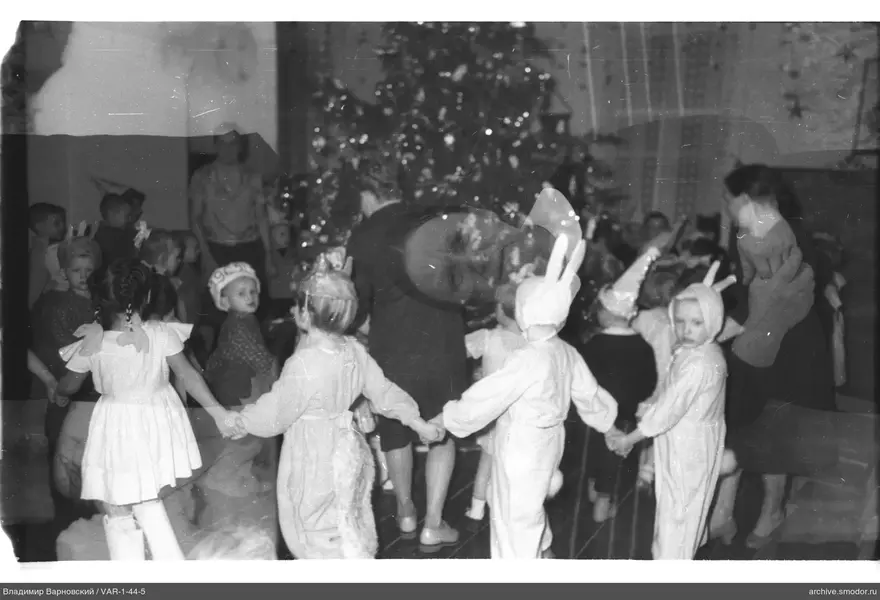 Kinder und Erwachsene im Kreis um den Weihnachtsbaum