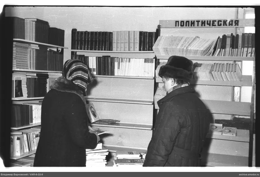 Два человека у книжных полок с надписью «ПОЛИТИЧЕСКАЯ»