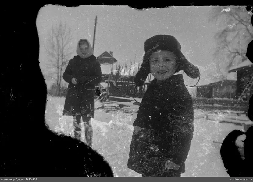 Мальчик в меховой шапке и женщина на улице
