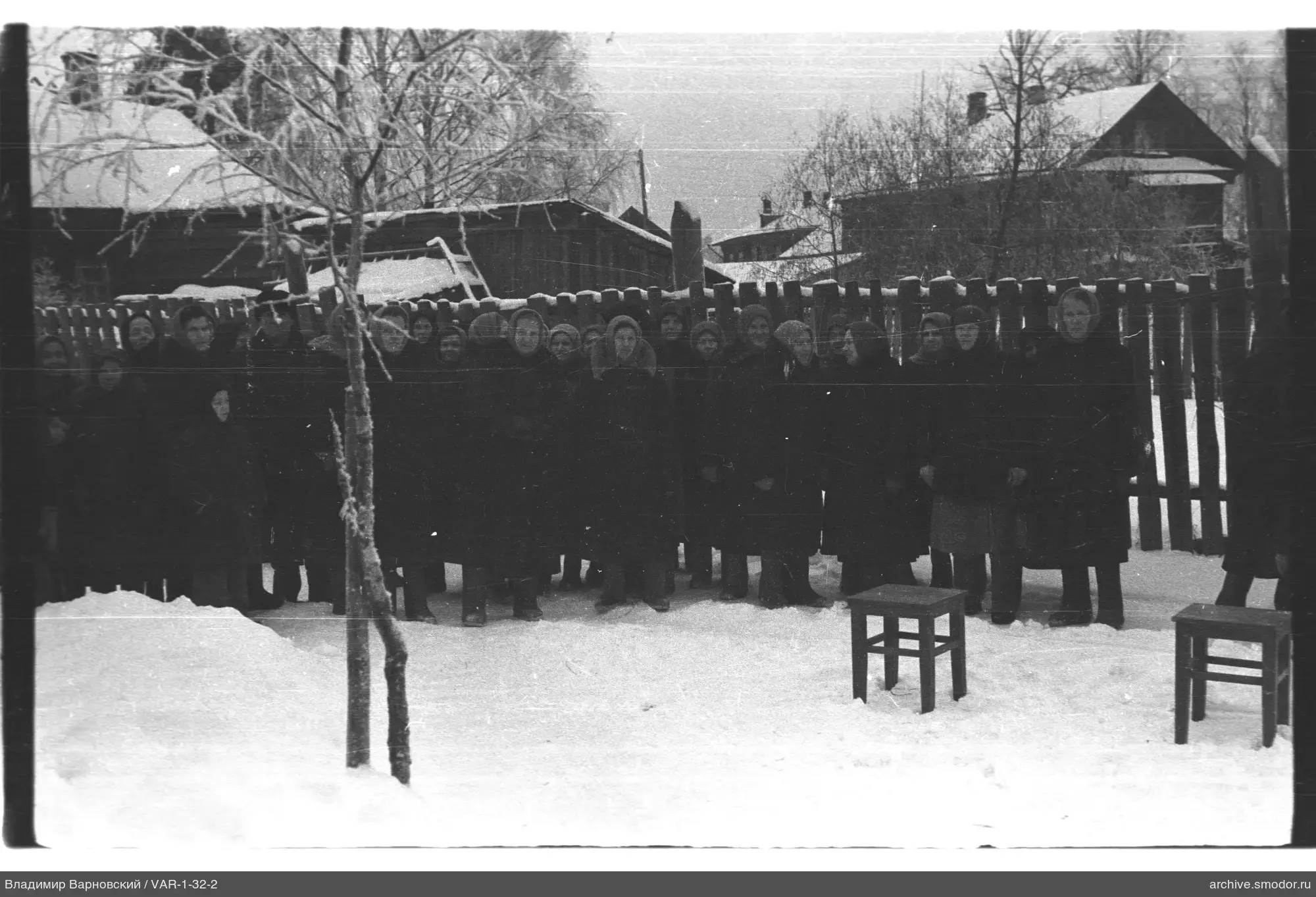 Group portrait on snow near a wooden fence