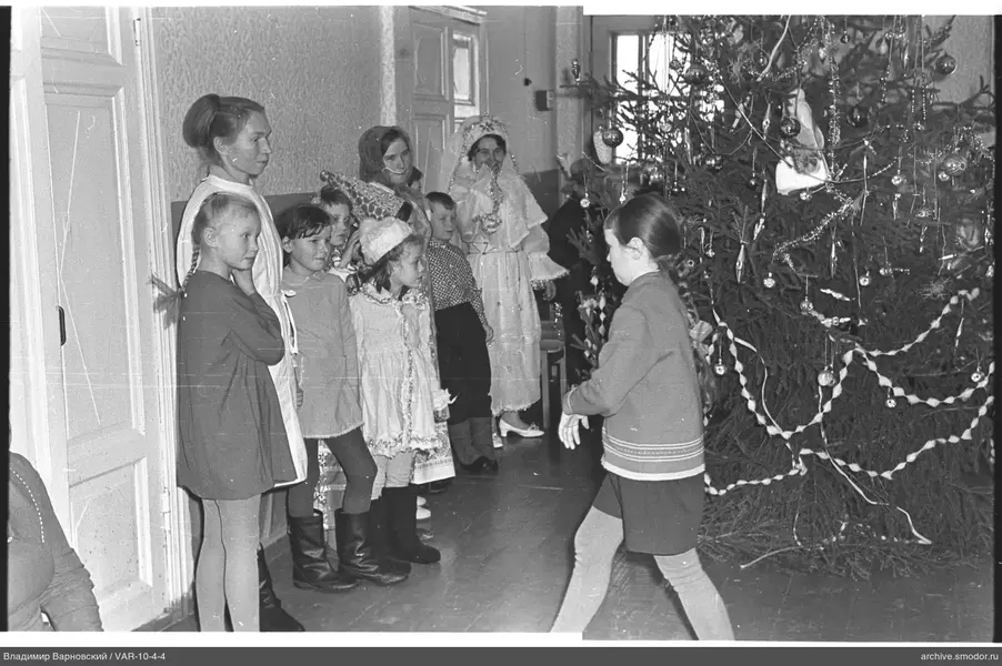 Kinder und Frauen neben geschmücktem Weihnachtsbaum