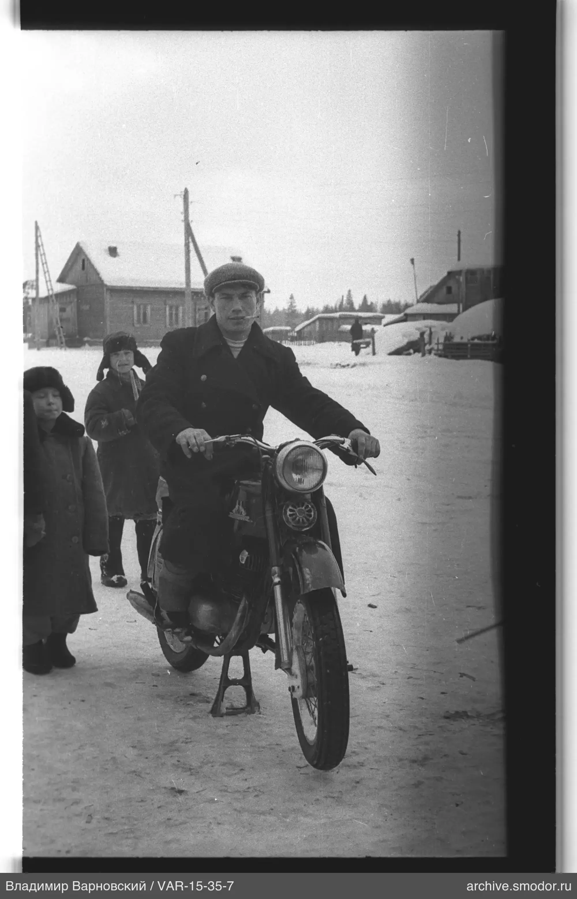Man on motorcycle with children in background