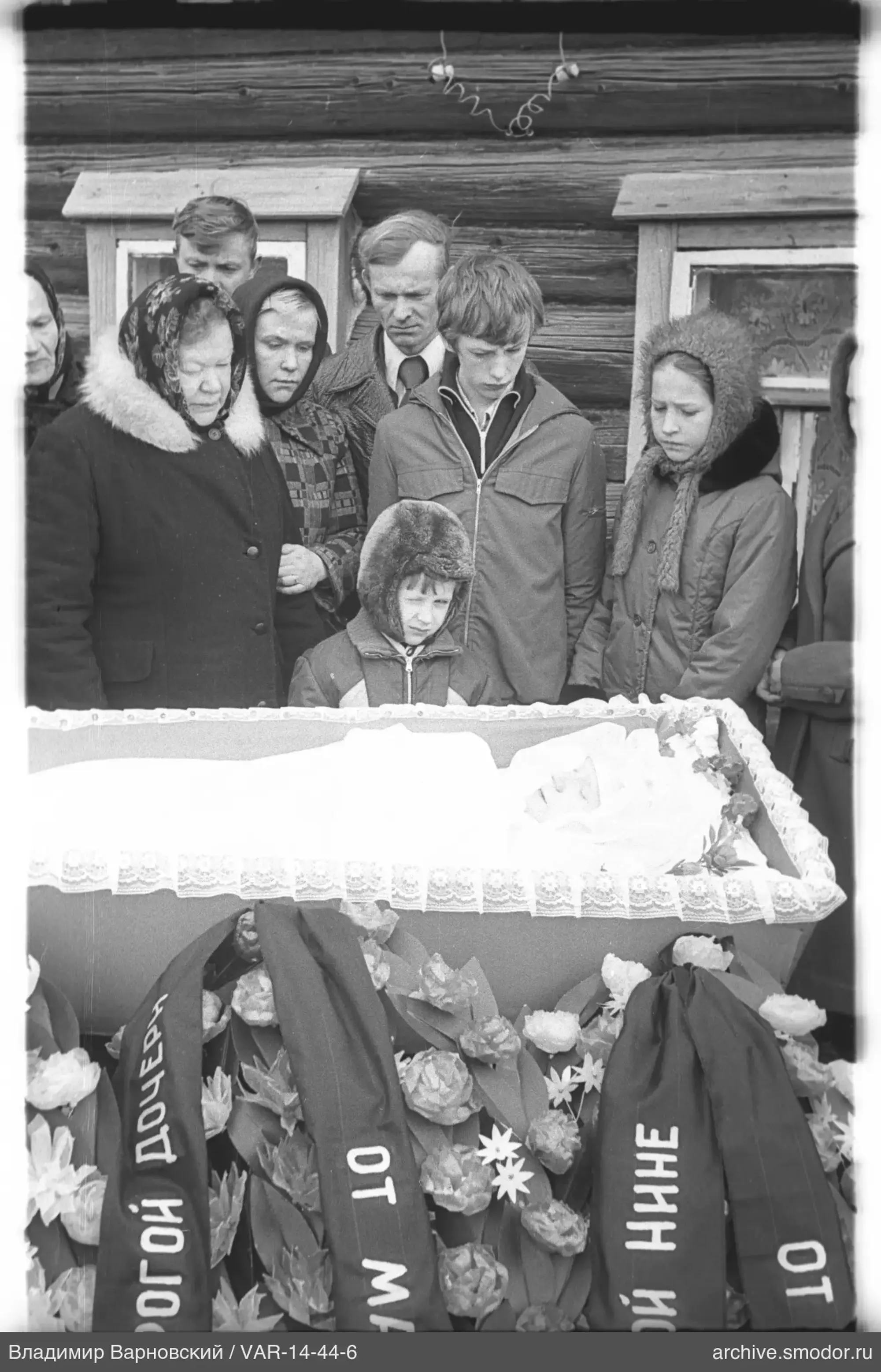 Gruppe vor Holzhaus mit Sarg
