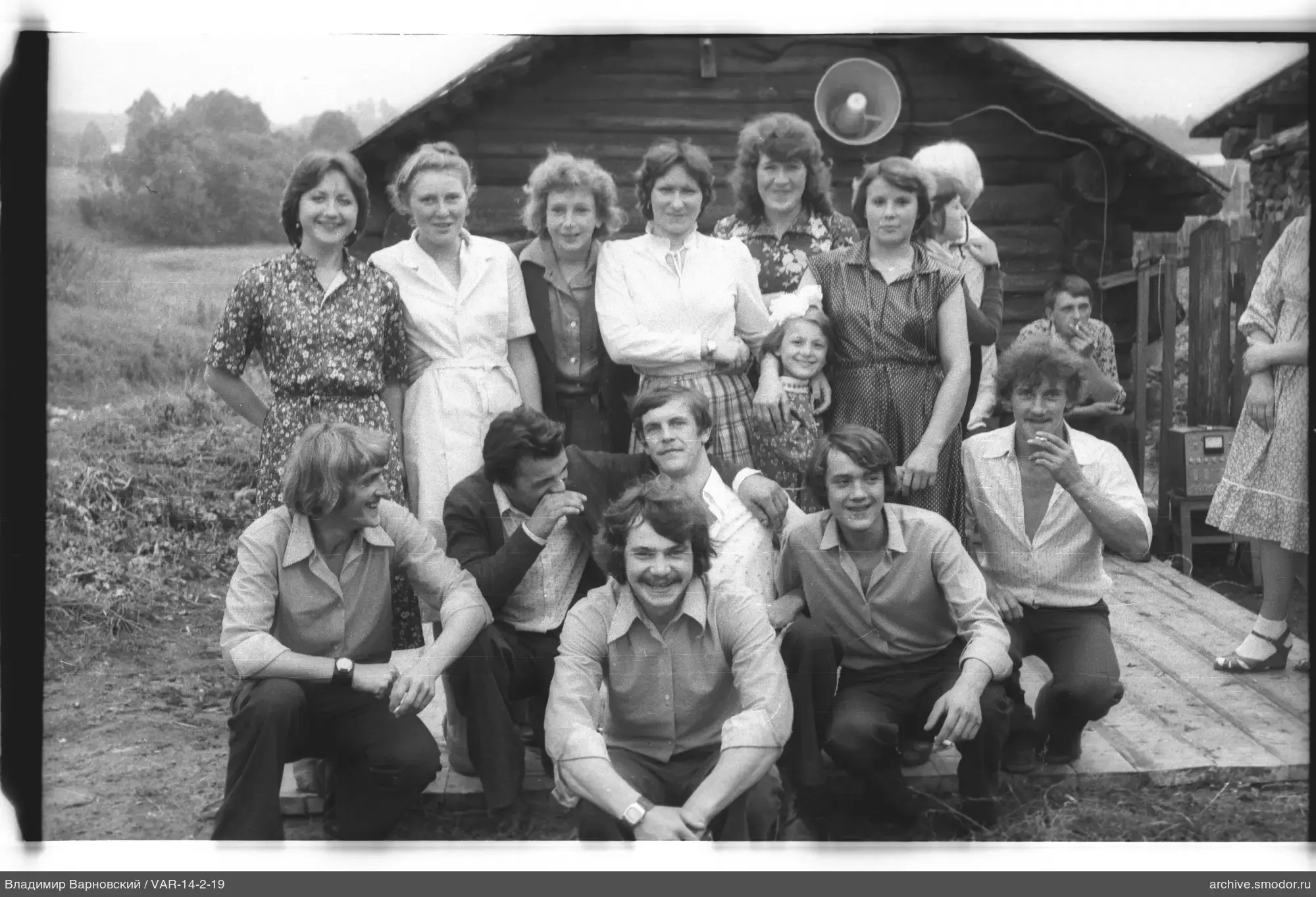 Gruppe von Männern und Frauen am Holzhaus