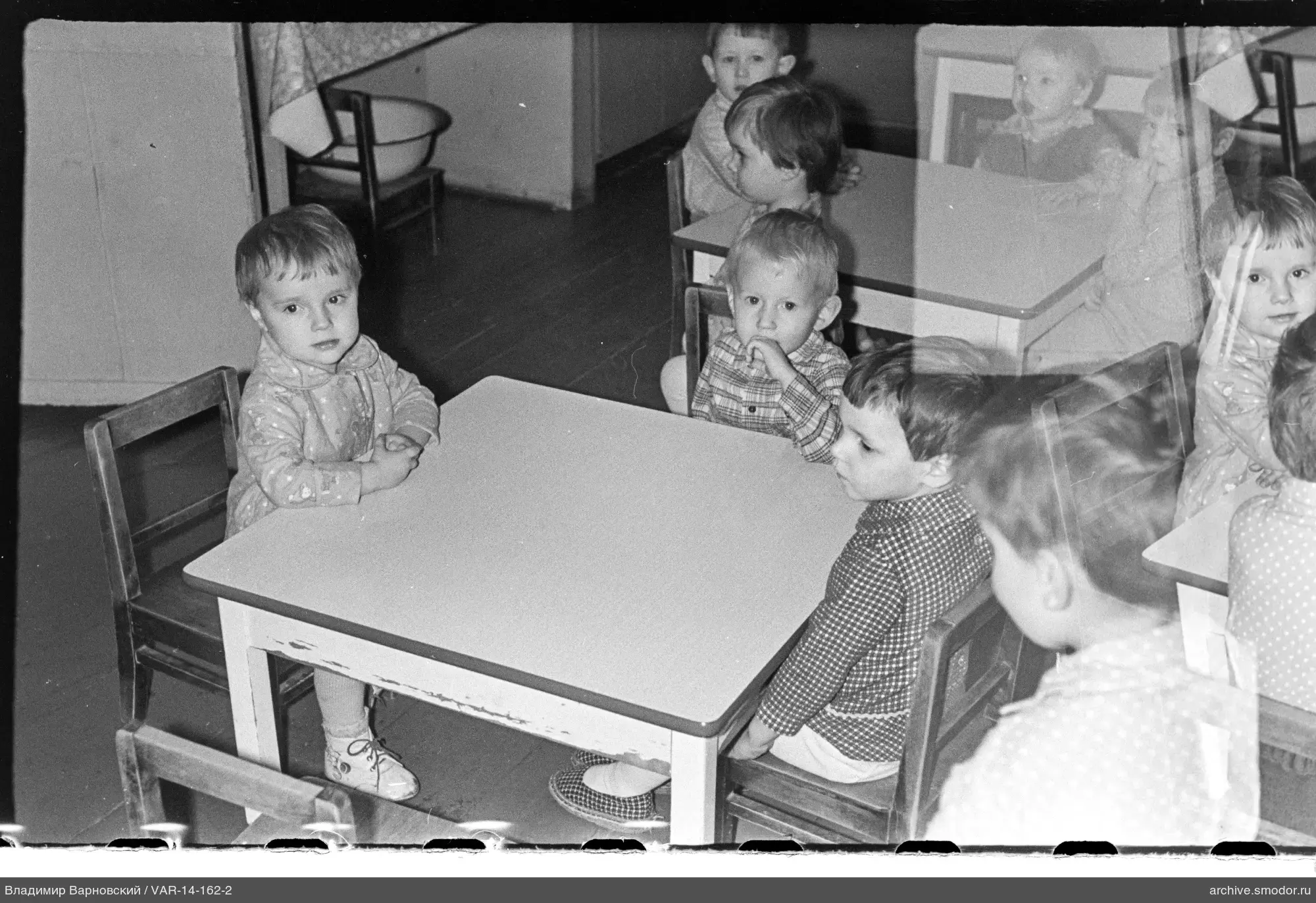Gruppenaufnahme von Kindern an Tischen