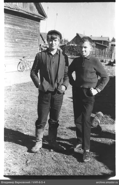 Two teenagers near a wooden house
