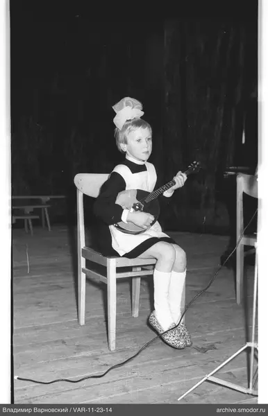 Child with balalaika on a chair