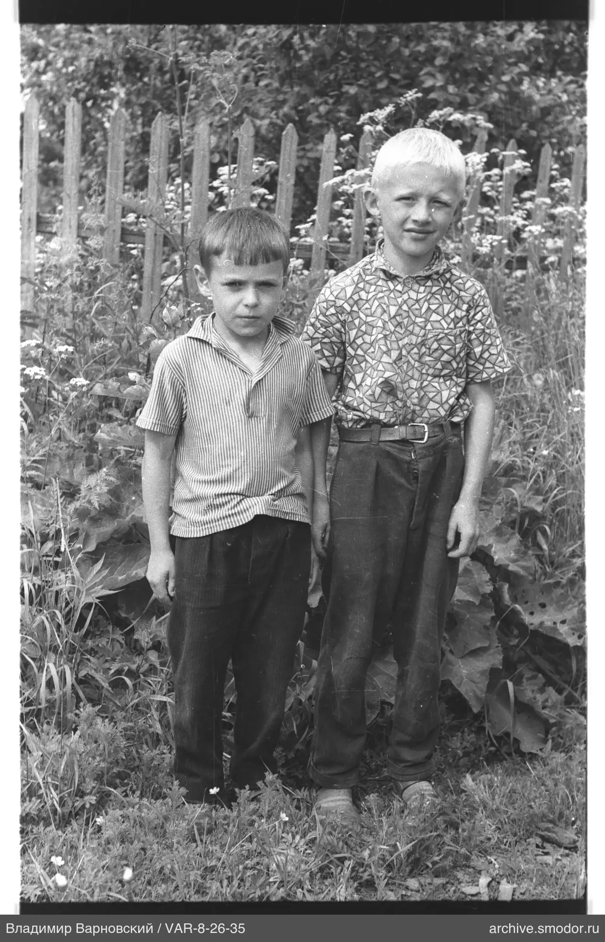 Two boys in front of a wooden fence