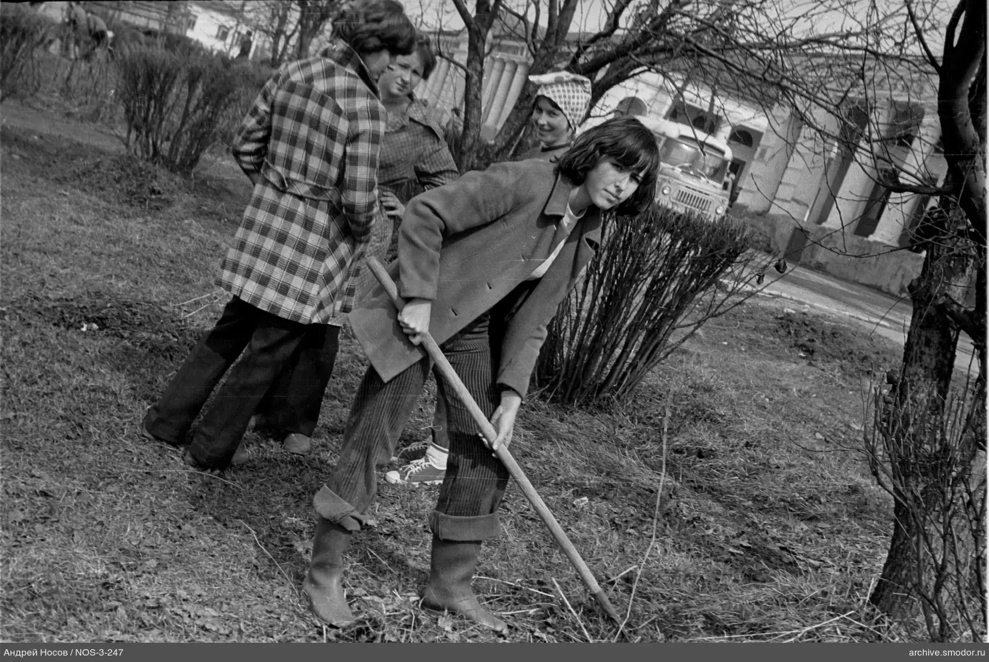 Frau mit Rechen und Gruppe von Frauen