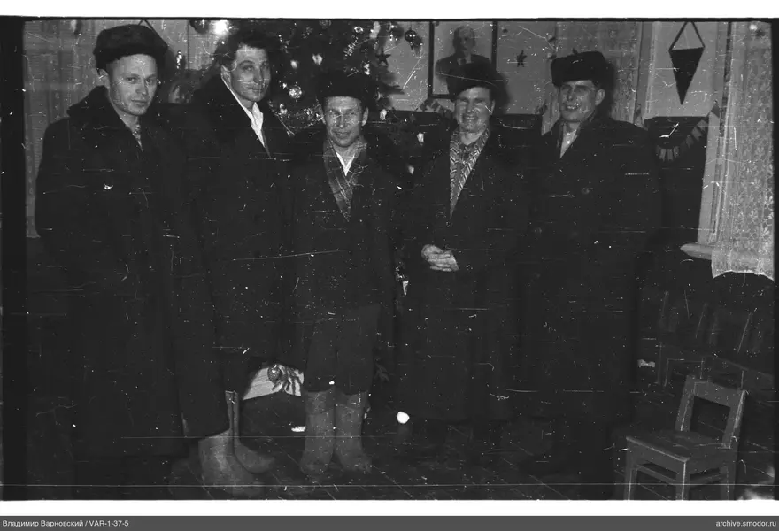 Gruppe von Männern in dunklen Mänteln bei Weihnachtsbaum