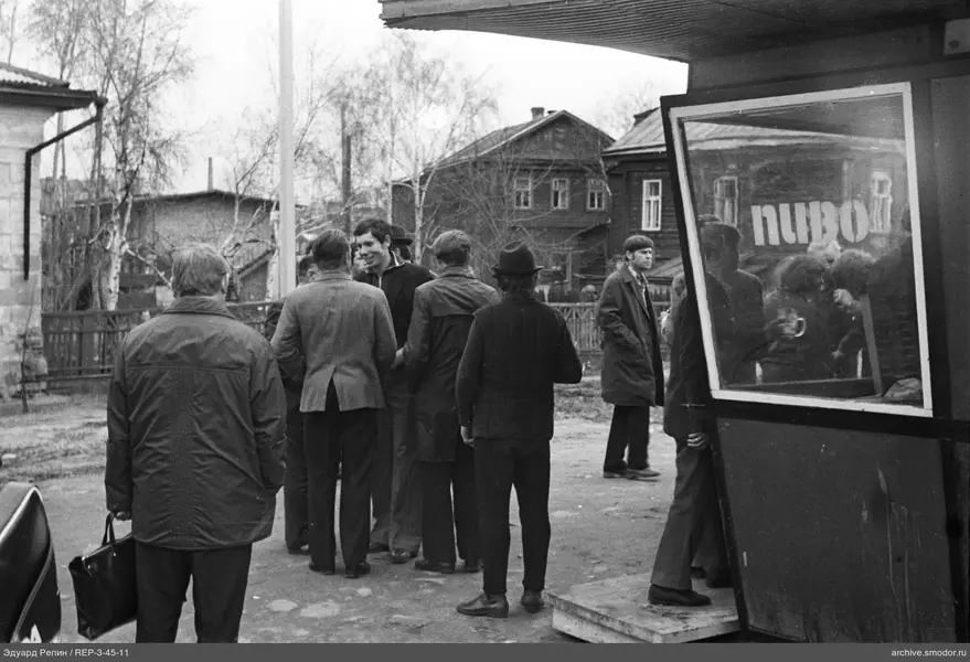 Gruppe von Männern auf der Straße bei Häusern und Kiosk