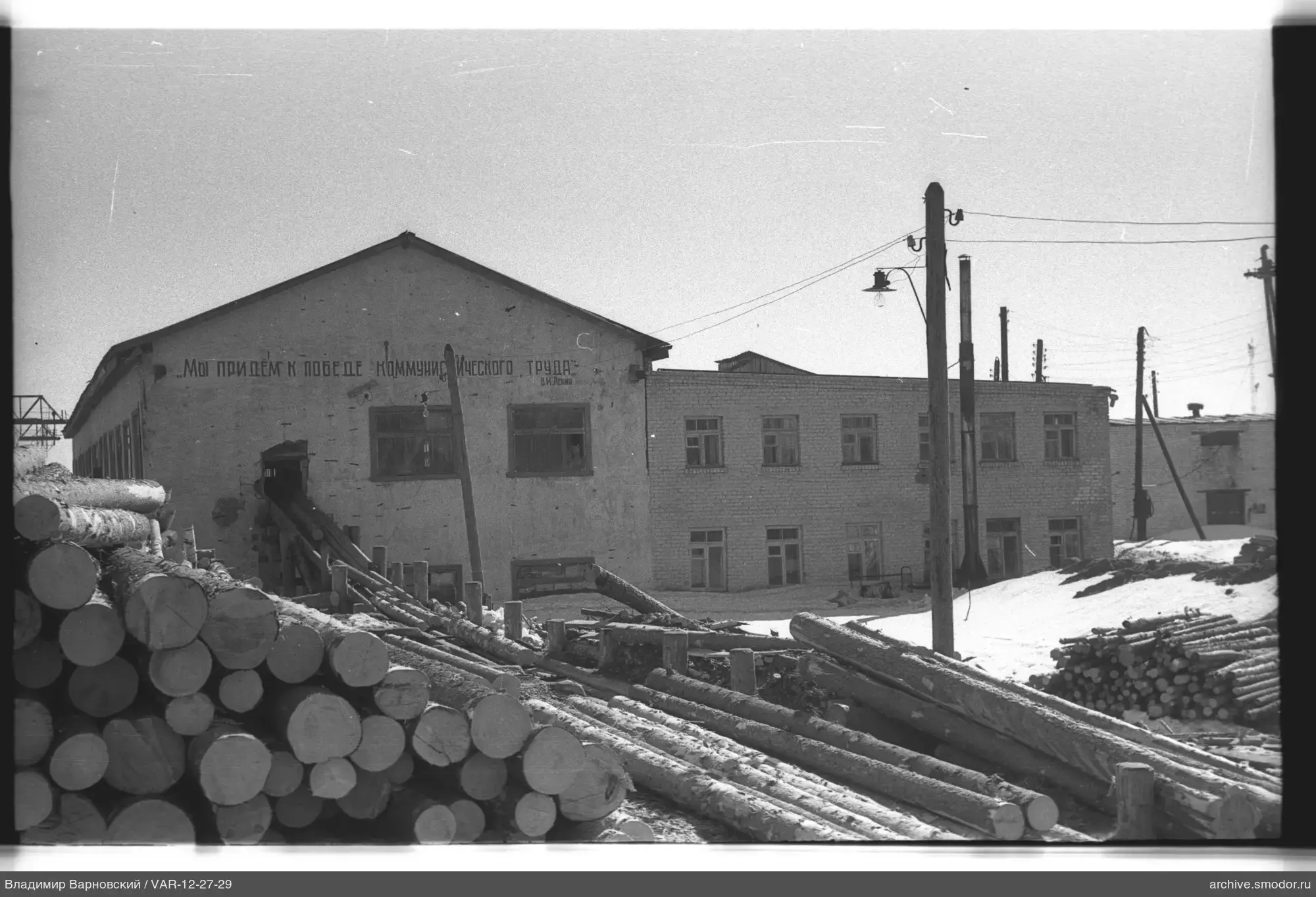 Stapel aus Baumstämmen und Gebäude mit Inschrift