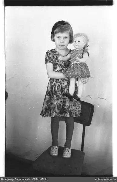 Mädchen mit Puppe auf Stuhl