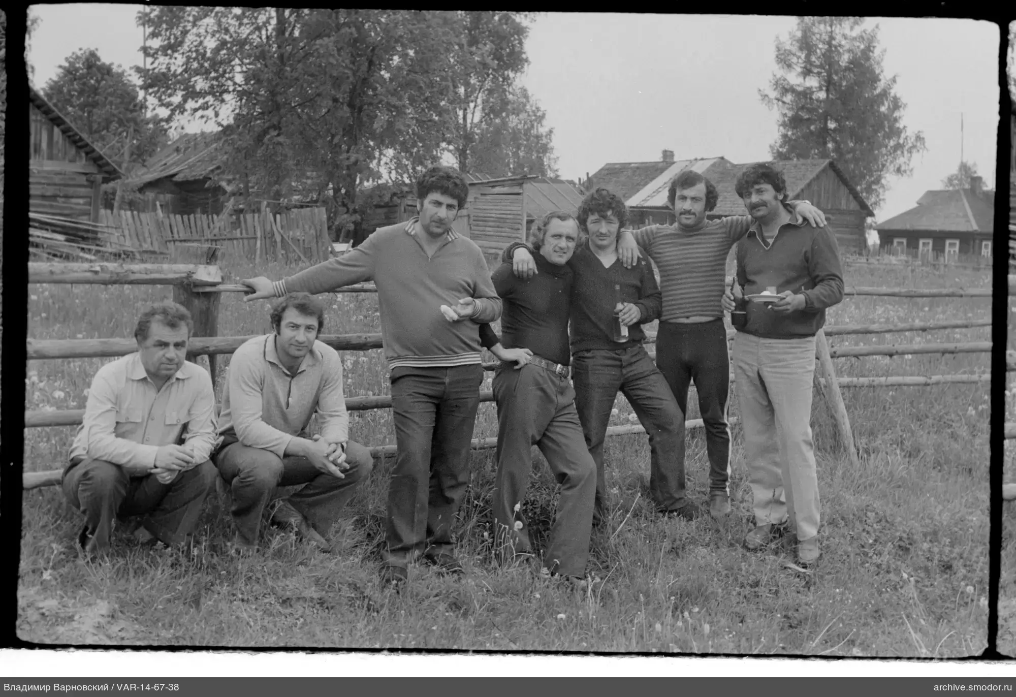 Gruppe von Männern vor Dorfhäusern